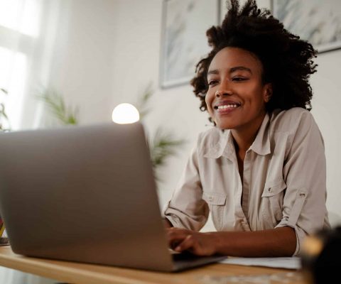 Young black smiling woman working at computer in an office.